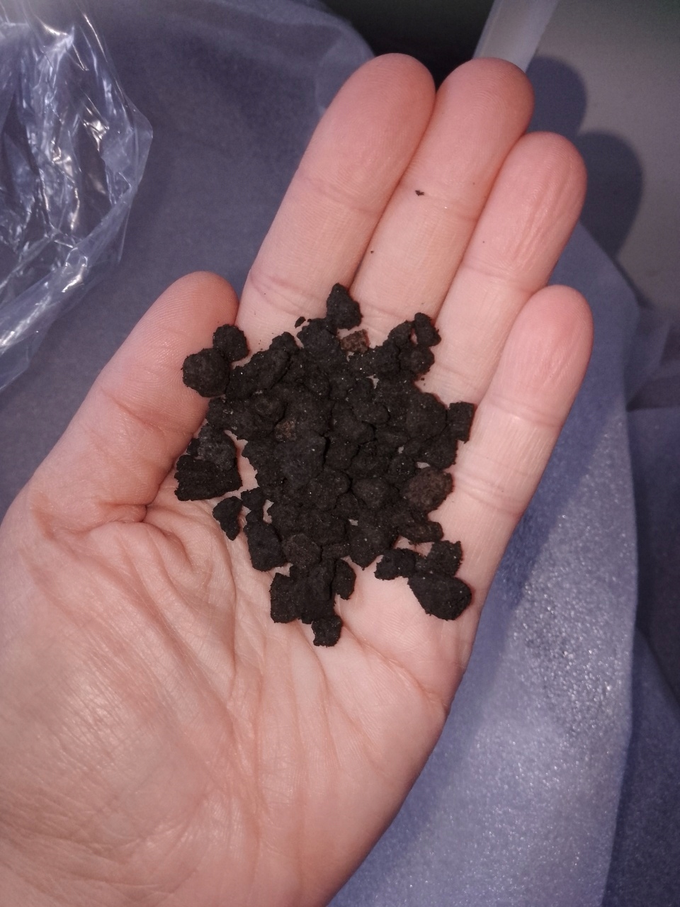Droben temno rjav mineralni granulat na dlani